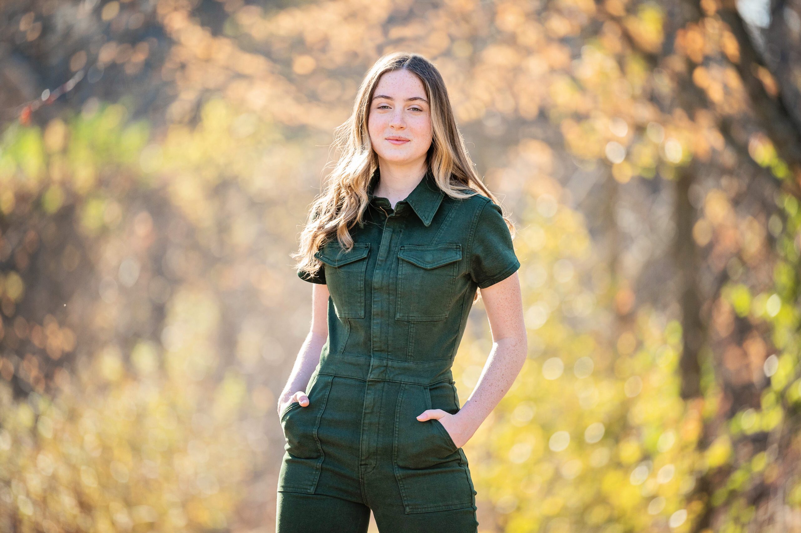 Senior pictures in Edina by Elissa Bean Photography featuring a high school senior in a dark green jumpsuit standing outdoors in warm autumn light.